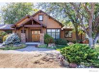 Charming home featuring a stone and wood facade, professionally landscaped yard, and a covered porch at 6224 Trevarton Dr, Longmont, CO 80503