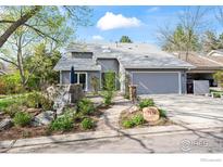 Charming gray home with a two-car garage and beautiful rock landscaping in the front yard at 7126 Cedarwood Cir, Boulder, CO 80301