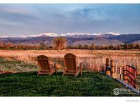 Mountain view backyard featuring two Adirondack chairs, wooden fence, and wild grass at 7929 Valmont Rd, Boulder, CO 80301