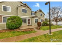 Inviting two-story townhome with lush green lawn, shrubbery, and concrete entry steps at 805 Summer Hawk Dr # Bb164, Longmont, CO 80504