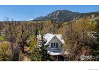 Charming home with white siding and roof, complemented by lush trees and mountain views at 838 University Ave, Boulder, CO 80302