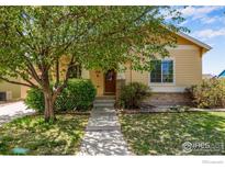 Charming yellow house with a well-manicured lawn and mature tree at 1038 Village Cir, Erie, CO 80516