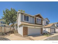 Two-story home featuring a gray garage door and brick accents at 10440 W 83Rd Ave, Arvada, CO 80005