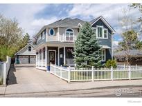 Charming two-story home with a white picket fence and beautifully landscaped front yard on a sunny day at 1121 Lincoln Ave, Louisville, CO 80027