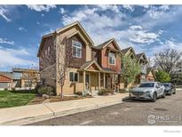 Beautiful townhome featuring a colorful exterior, a well-manicured lawn, and a private walkway at 1320 Kestrel Ln # E, Longmont, CO 80501