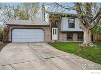 Charming two-story home with a brick facade, attached garage, a well-manicured lawn, and mature trees at 13755 W 65Th Dr, Arvada, CO 80004