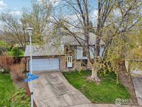 Charming home featuring a well-kept lawn, mature tree, and a two-car garage on a tree-lined street at 13755 W 65Th Dr, Arvada, CO 80004