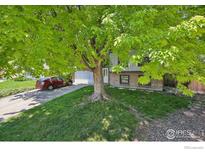 Charming brick home featuring an attached garage, driveway, and landscaped front yard at 13755 W 65Th Dr, Arvada, CO 80004