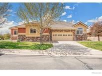 Charming single-Gathering home with a two-car garage and stone accents under a blue sky at 1993 Cedarwood Pl, Erie, CO 80516
