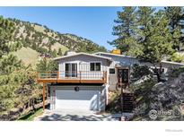 Hillside two-story home with a front deck over the attached garage and mature trees at 2345 Point Of Pines Dr, Boulder, CO 80302