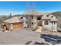 Stunning exterior of a stone and stucco home with a tile roof and a large driveway at 27921 Alabraska Ln, Evergreen, CO 80439