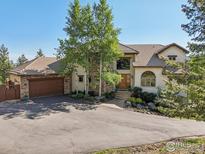 Inviting home featuring a stone facade, mature trees, tile roof, and a circular driveway at 27921 Alabraska Ln, Evergreen, CO 80439