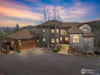 Beautiful home featuring a tile roof, stone accents, a spacious driveway, and a large garage at 27921 Alabraska Ln, Evergreen, CO 80439