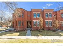 Inviting brick townhouse with a well-maintained lawn, complemented by mature trees and manicured landscaping at 2890 Curtis St, Denver, CO 80205