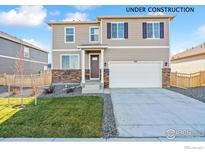 Charming two-story home with tan siding, stone accents, a well-maintained lawn, and a two-car garage at 4732 Windmill Dr, Brighton, CO 80601