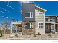 Charming home featuring a mix of stone and vinyl siding, a balcony, and a well-kept gravel yard at 799 Robert St, Longmont, CO 80503