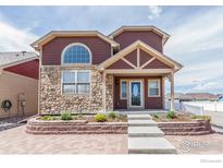 Charming two-story home featuring a stone facade, manicured lawn, and inviting entryway at 800 Gateway Park Ln, Berthoud, CO 80513