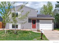 Charming two-story home with gray siding, a red front door, and a well-maintained lawn at 10683 Newcombe Way, Broomfield, CO 80021