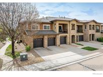 Attractive townhome featuring a stone facade, private balconies, and individual garages for each unit at 1122 Olympia Ave # 12H, Longmont, CO 80504