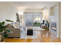 Inviting living room with a fireplace, cozy seating, and sliding glass doors to a private balcony at 1122 Olympia Ave # 12H, Longmont, CO 80504