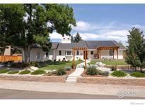 Inviting single-story home with a well-manicured lawn, solar panels, and charming pergola at 14117 W 58Th Pl, Arvada, CO 80004