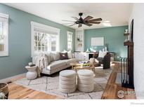 Inviting living room with hardwood floors, a ceiling fan, and ample natural light from the large window at 14117 W 58Th Pl, Arvada, CO 80004