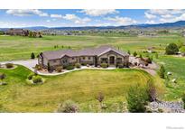 Sprawling tan home featuring stone accents, meticulous landscaping, and mountain views at 1868 Preserve Dr, Berthoud, CO 80513