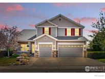 Charming two-story home with a two car garage, landscaped front yard, and red shutters at 665 Glenarbor Cir, Longmont, CO 80504