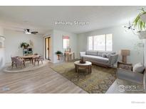 Virtually staged living room showcasing stylish furniture on sleek wood floors, with view of the yard through windows at 1100 Bacchus Dr # A, Lafayette, CO 80026
