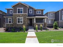 Charming two-story home with stone accents and a well-manicured front yard under a bright blue sky at 11933 Norfolk Ct, Commerce City, CO 80022