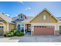 Inviting townhome featuring a landscaped front yard, covered porch, and attached two-car garage at 14394 W 88Th Dr # C, Arvada, CO 80005