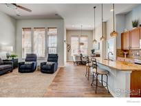 Open-concept living space with hardwood floors, kitchen island, and large windows providing natural light at 14394 W 88Th Dr # C, Arvada, CO 80005