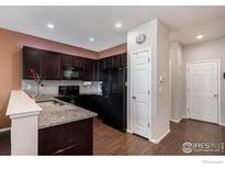 Stylish kitchen with dark cabinets, granite countertops, and black appliances at 16058 E Elk Dr, Denver, CO 80239