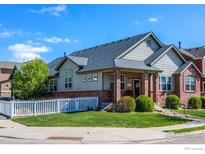 Charming home with brick accents, a landscaped front yard, and a white picket fence at 2196 Winding Dr, Longmont, CO 80504