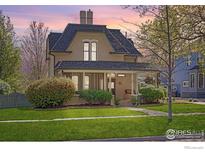 Charming two-story home featuring a well-manicured lawn, mature trees, and an inviting front porch at 318 Pratt St, Longmont, CO 80501