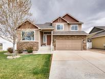 Charming two-story home with stone accents, a manicured lawn, and an attached two-car garage at 3338 Auklet Dr, Berthoud, CO 80513