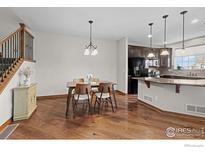 Bright dining area features hardwood floors, chandelier, and staircase access to the upper level at 4822 Raven Run, Broomfield, CO 80023