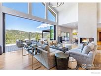 Bright living room boasts a fireplace, hardwood floors, and glass doors to an outdoor seating area with mountain views at 50 Wildwood Ln, Boulder, CO 80304