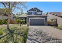 Charming two-story home featuring a well-maintained lawn, mature trees, and a two-car garage at 5822 Shenandoah Ave, Firestone, CO 80504