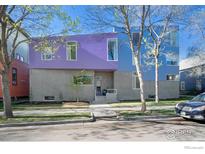 Striking two-story home featuring modern architecture, a concrete facade, and eye-catching blue and purple accents at 1025 Neon Forest Cir, Longmont, CO 80504