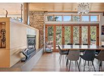 Elegant dining room boasts a stone fireplace, floor-to-ceiling windows, and access to a serene deck at 1127 Valley Ln, Boulder, CO 80302