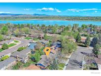 Stunning aerial view of a lakeside community with lush trees and a tranquil lake backdrop at 19 University Cir, Longmont, CO 80503