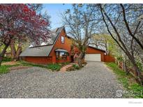 Inviting exterior view of a unique chalet-style home with brick accents and a well-maintained gravel driveway at 4731 Jay Rd, Boulder, CO 80301