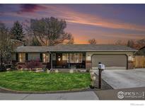 Charming ranch-style home featuring a well-manicured lawn, brick accents, and an attached two-car garage against a vivid sunset sky at 7960 Estes Ct, Arvada, CO 80005