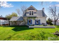 Charming two-story home with blue shutters, climbing vines, a brick retaining wall and a lush green lawn at 1503 Balsam Ave, Boulder, CO 80304