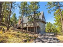 Stunning mountain home featuring a large deck and a backdrop of lush forest and blue sky at 65 Bristlecone Way, Boulder, CO 80304