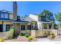 Inviting townhouse featuring a stone chimney and fenced yard with garden, enhancing its curb appeal and outdoor living space at 8750 Allison Dr # B, Westminster, CO 80005