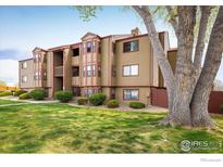 Inviting two-story exterior of a condo building featuring charming curb appeal, mature trees, and landscaped lawn at 8770 Corona St # 101, Denver, CO 80229