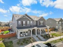 Charming two-story home boasts a welcoming front porch, grey siding, and stone accents at 922 Colorado River Ave, Brighton, CO 80601