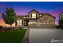Charming two-story home featuring a stone facade, a well-manicured lawn, and a spacious two car garage at 955 Horizon Ct, Erie, CO 80516